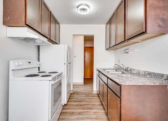 A kitchen with white appliances and brown cabinets.