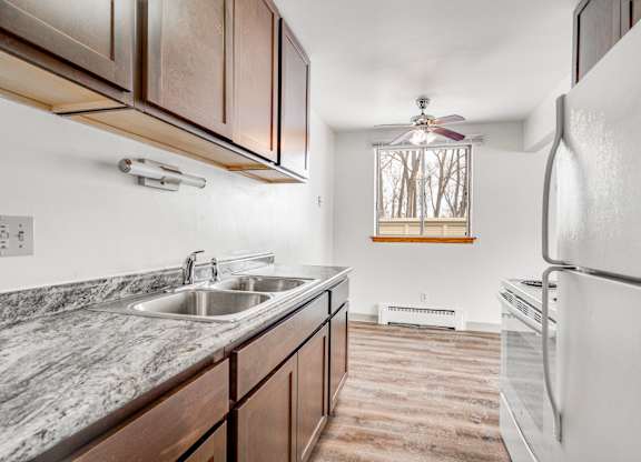 A kitchen with a marble countertop and a white refrigerator.