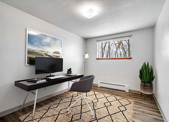 A room with a desk, chair, and a painting on the wall.