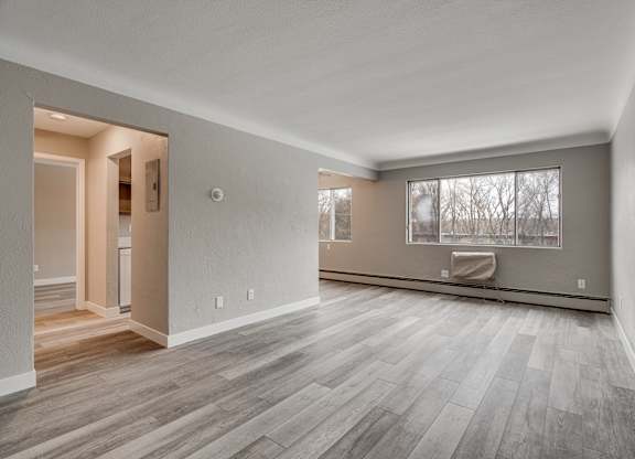 A room with wooden flooring and a window with a view of trees.