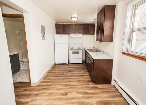 A kitchen with white appliances and brown cabinets.