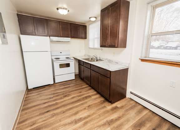 A kitchen with white appliances and brown cabinets.