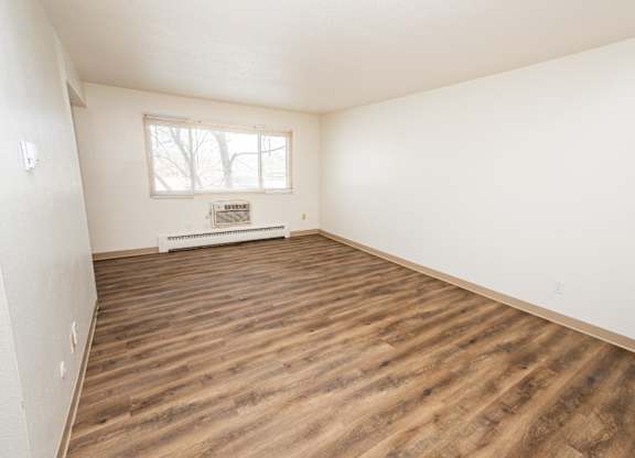 A room with wooden flooring and a window.