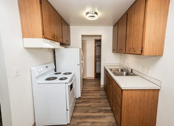 A kitchen with a white stove and wooden cabinets.