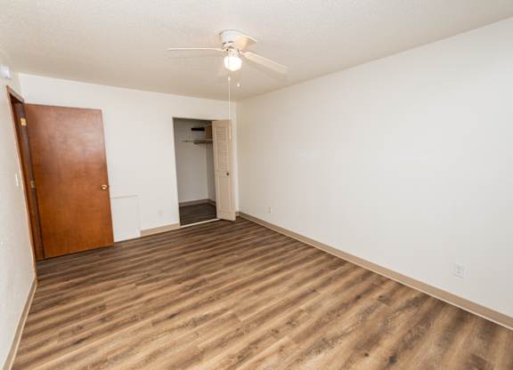 A room with a ceiling fan and wooden flooring.