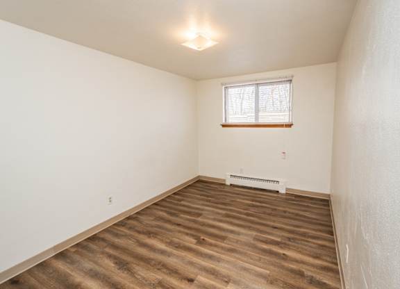 A room with wooden flooring and a window.