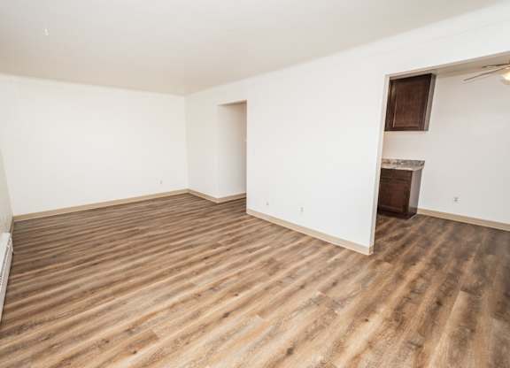 Empty room with wooden flooring and white walls.