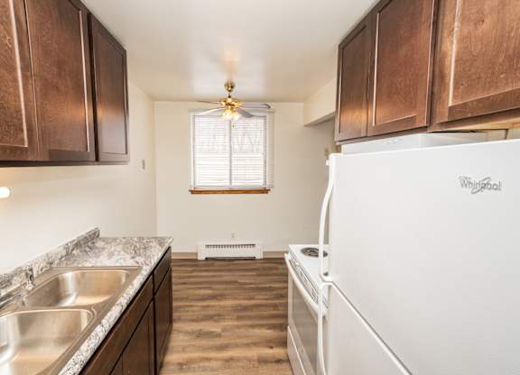 A kitchen with a white fridge and wooden cabinets.