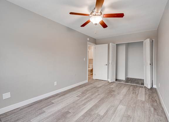 A room with a ceiling fan and a wooden floor.