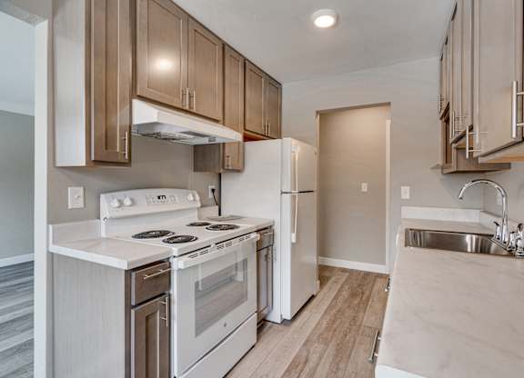 A kitchen with a stove, refrigerator, and sink.