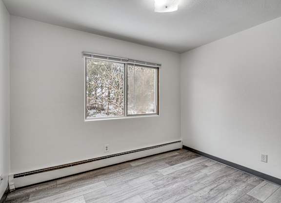 A room with a window and a wooden floor.