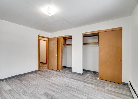 A room with a grey floor and white walls with three wooden doors.