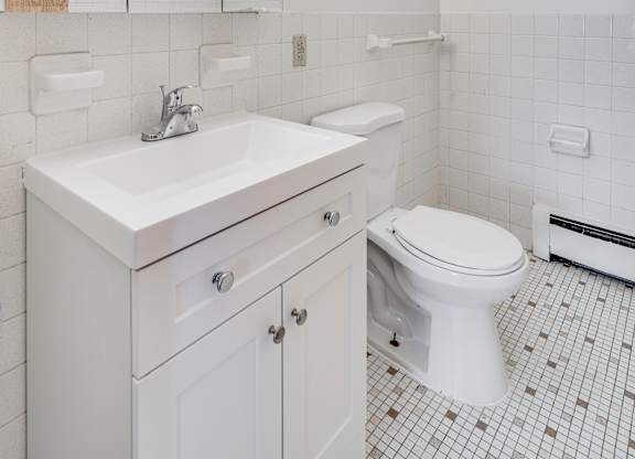 A white bathroom with a sink, toilet and mirror.