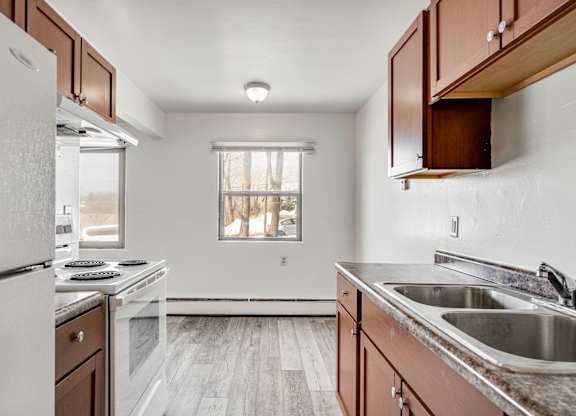 A kitchen with a white fridge, stove, and sink.