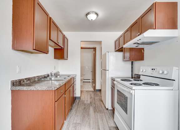 A kitchen with white appliances and wooden cabinets.