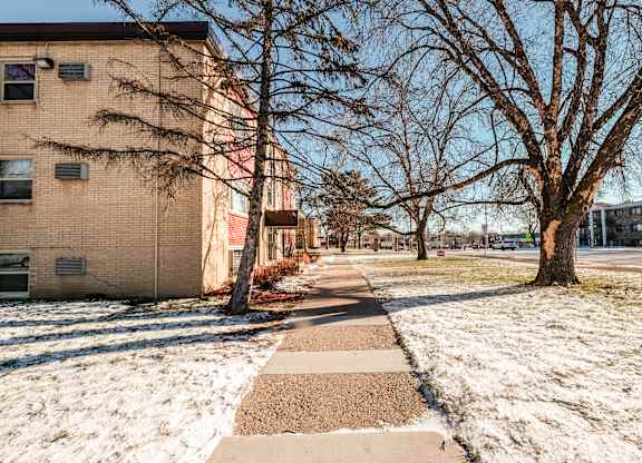 A snow-covered sidewalk leads to a brick building.
