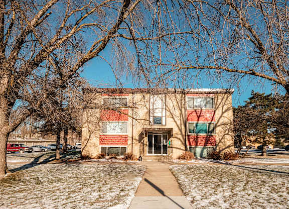 A building with a red and green striped wall is surrounded by bare trees.