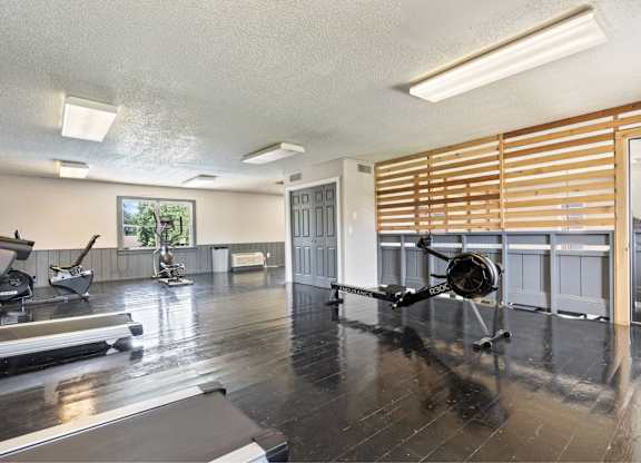 A room with a treadmill, a chair, and a plane on the floor.