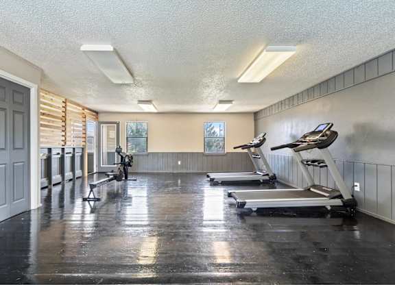 A gym with treadmills and a bench.