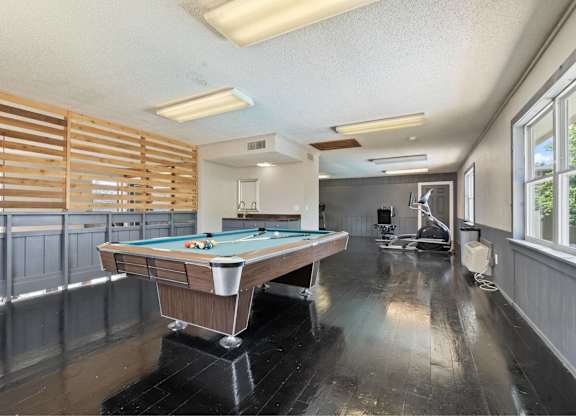 A pool table in a room with wooden blinds on the windows.
