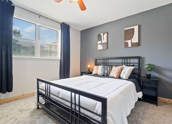 A bedroom with a bed, nightstand, and a ceiling fan.