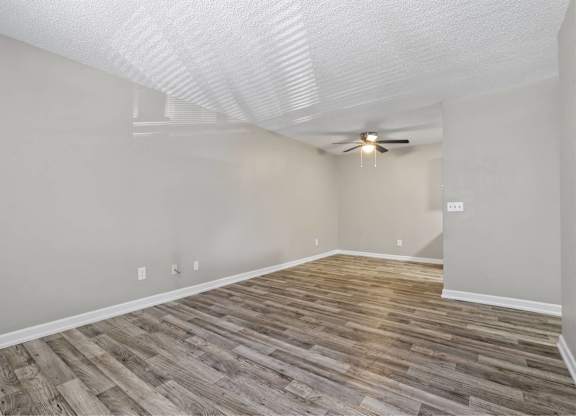 A room with a ceiling fan and wooden flooring.