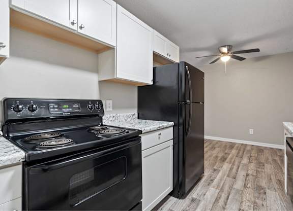 A black stove and oven in a kitchen with a refrigerator and cabinets.