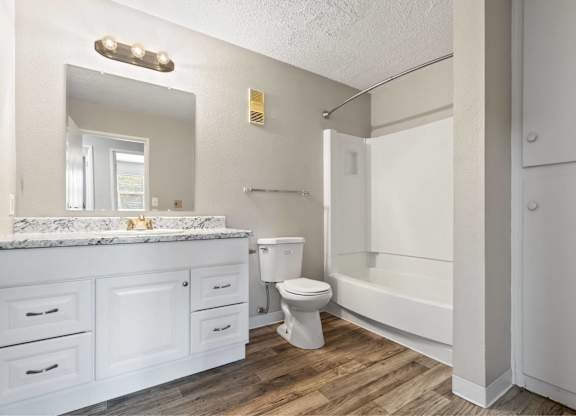 A white bathroom with a marble countertop and a white toilet.