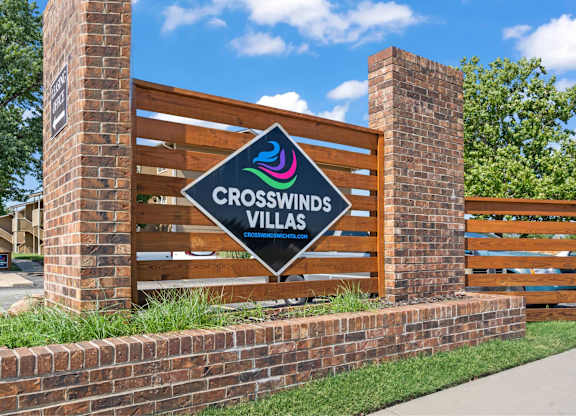 A sign for Crosswinds Villas is displayed on a brick wall.
