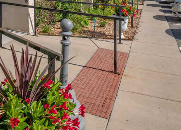 A row of apartment buildings with balconies and flower pots on the sidewalk.