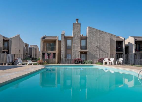 A swimming pool in front of a building with a clear blue sky.
