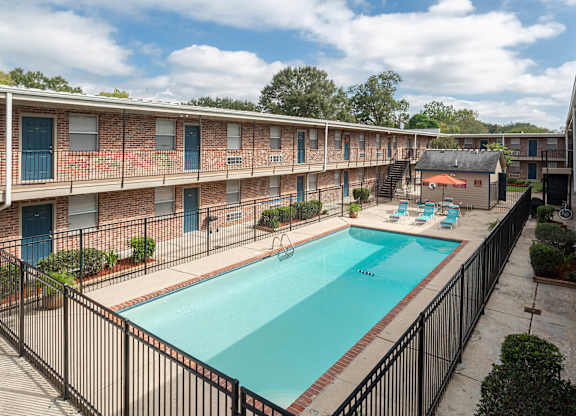 A swimming pool in a courtyard surrounded by a black fence.