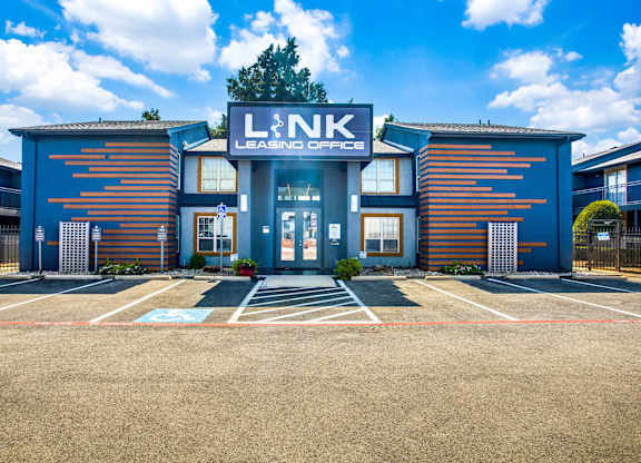 The image shows a building with the letters L&NK on it, surrounded by a parking lot.