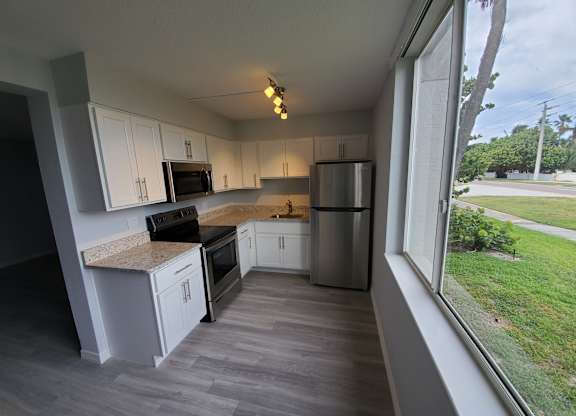 A kitchen with white cabinets and a marble countertop.