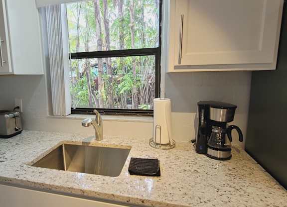 A kitchen with a sink, toaster, and coffee maker.