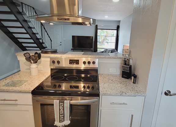 A kitchen with a stove top oven and a stainless steel range hood.