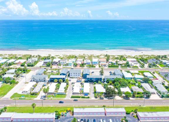 A beachfront view of a small town with buildings and a parking lot.
