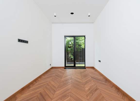 A room with a wooden floor and a glass door leading outside.