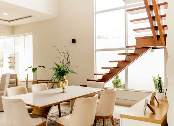 A dining room with a wooden table and white chairs.