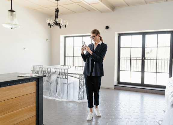 A woman in a black outfit is standing in a room with a wooden counter and a chandelier.