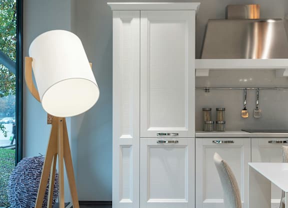 A white lamp stands next to a white cabinet in a kitchen.