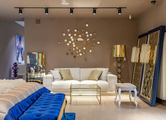 A living room with a white couch and a blue tufted bench.