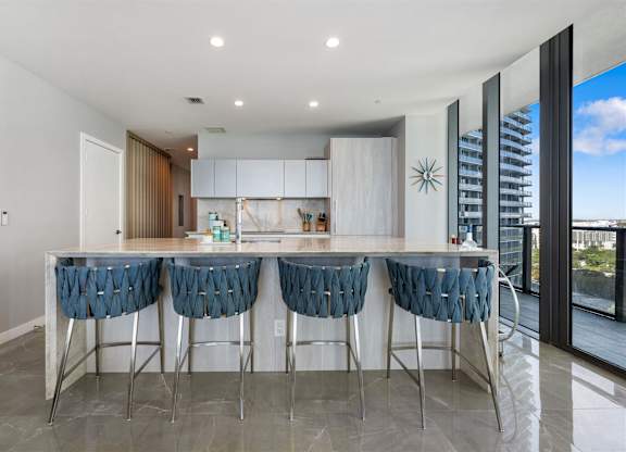 A modern kitchen with a bar area and blue chairs.