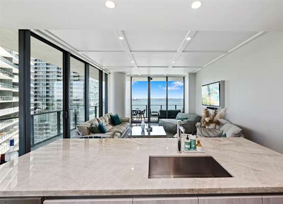 A modern kitchen with a marble countertop and a view of the city.
