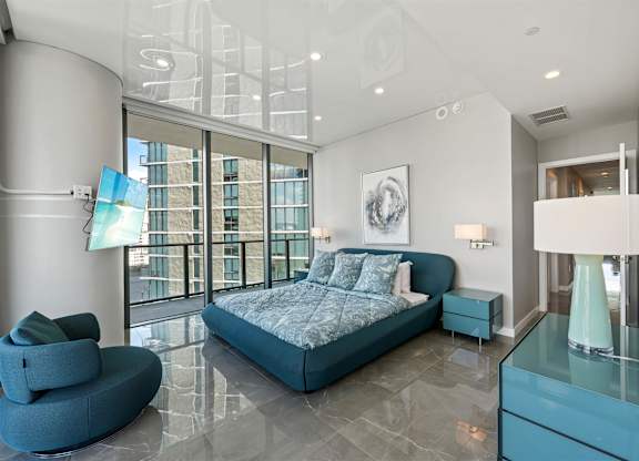 A bedroom with a large bed and a blue chair.