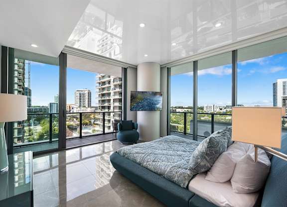 A modern bedroom with a large bed and a view of the city.