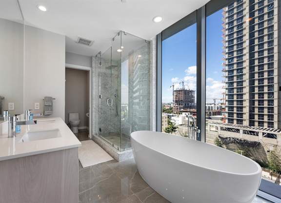 A modern bathroom with a large tub and a view of the city.