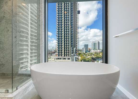 A white bathroom with a large tub and a glass door.
