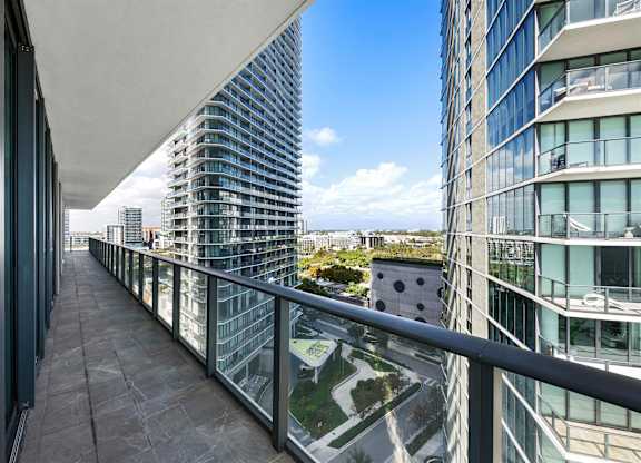 A balcony with a glass railing overlooks a cityscape.