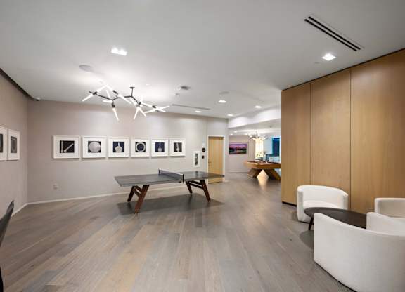A room with a ping pong table and chairs.